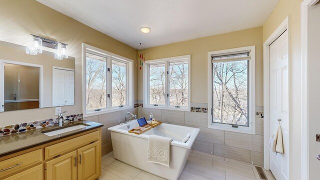 bathroom with tile walls, vanity, tile patterned floors, and a bathing tub