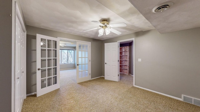 spare room with light colored carpet, ceiling fan, and french doors