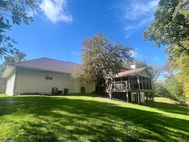 rear view of house featuring a wooden deck, a sunroom, and a lawn