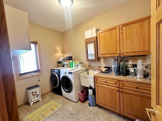 112 Bay Rd, Coleraine, MN 55722 - laundry area featuring washer and clothes dryer, cabinet space, and light tile patterned floors