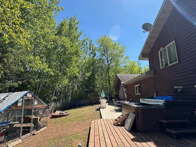112 Bay Rd, Coleraine, MN 55722 - view of yard featuring a hot tub, a wooden deck, and an outdoor structure