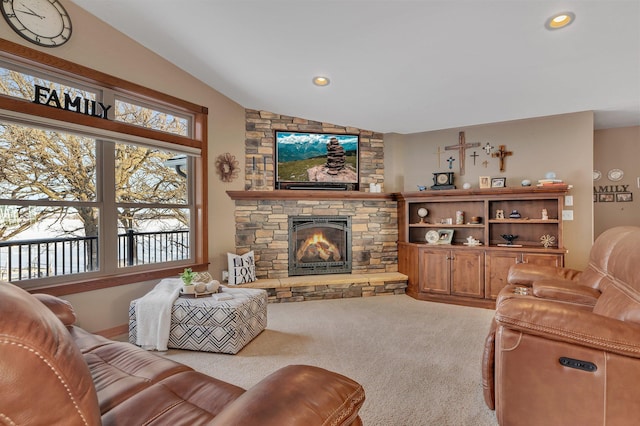 carpeted living room with a stone fireplace and lofted ceiling