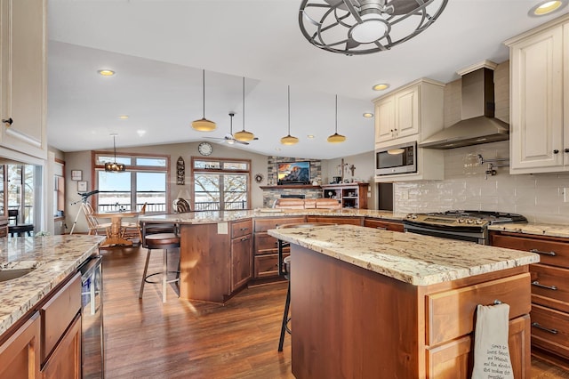 kitchen featuring a center island, wall chimney range hood, and a kitchen bar