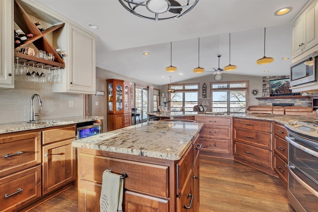 kitchen with a kitchen island, appliances with stainless steel finishes, pendant lighting, lofted ceiling, and backsplash