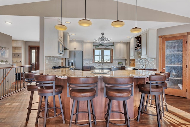 kitchen featuring hanging light fixtures, light stone countertops, a breakfast bar area, and kitchen peninsula