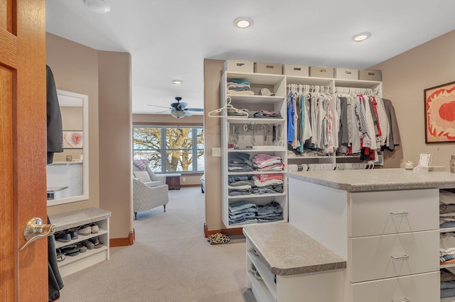 walk in closet with ceiling fan and light colored carpet