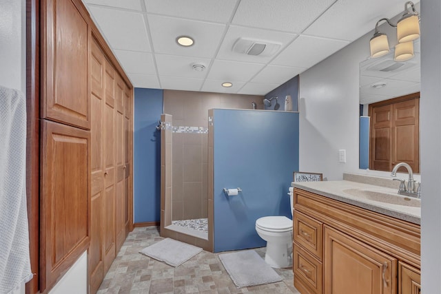 bathroom featuring walk in shower, a paneled ceiling, vanity, and toilet