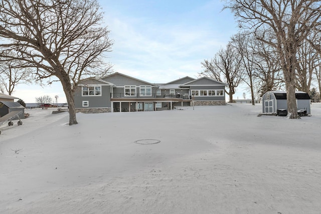 snow covered rear of property with a storage unit