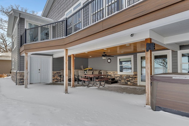 snow covered patio featuring a hot tub, a balcony, and ceiling fan