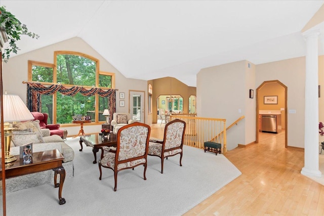 living area featuring lofted ceiling, light wood finished floors, decorative columns, and baseboards