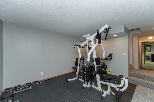 exercise room featuring baseboards and a textured ceiling