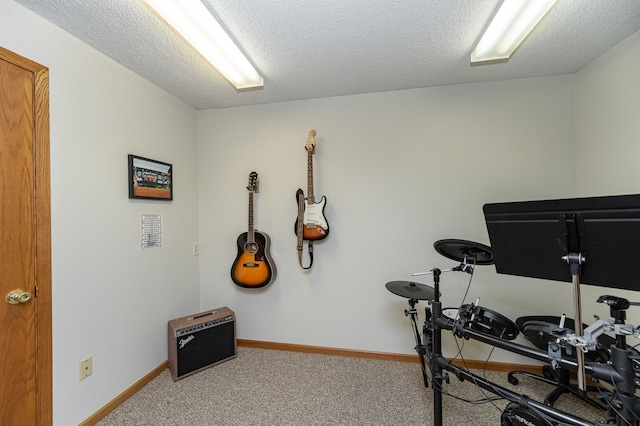 workout area featuring carpet flooring, a textured ceiling, and baseboards