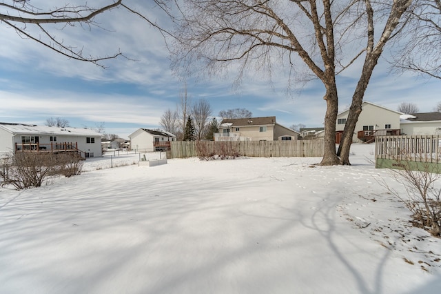 yard layered in snow featuring a residential view and fence