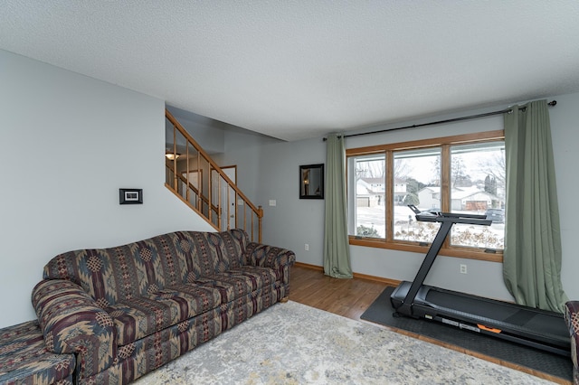 exercise area with a textured ceiling, baseboards, and wood finished floors