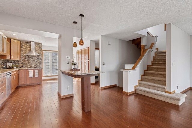 kitchen with hardwood / wood-style flooring, wall chimney exhaust hood, a breakfast bar area, and backsplash