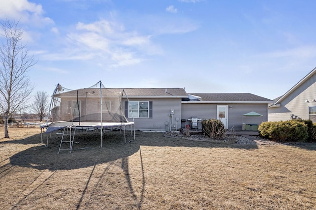 rear view of property featuring a wooden deck and a trampoline