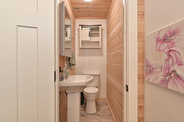 bathroom featuring toilet, wooden walls, hardwood / wood-style floors, and wooden ceiling