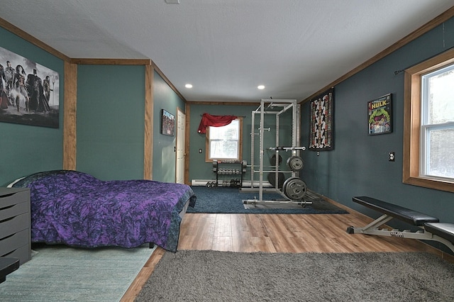 bedroom with wood-type flooring, a textured ceiling, and crown molding