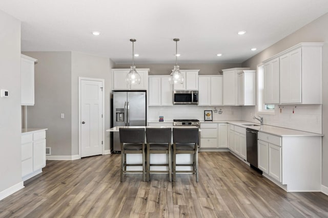 kitchen with appliances with stainless steel finishes, white cabinetry, hanging light fixtures, a center island, and dark hardwood / wood-style flooring