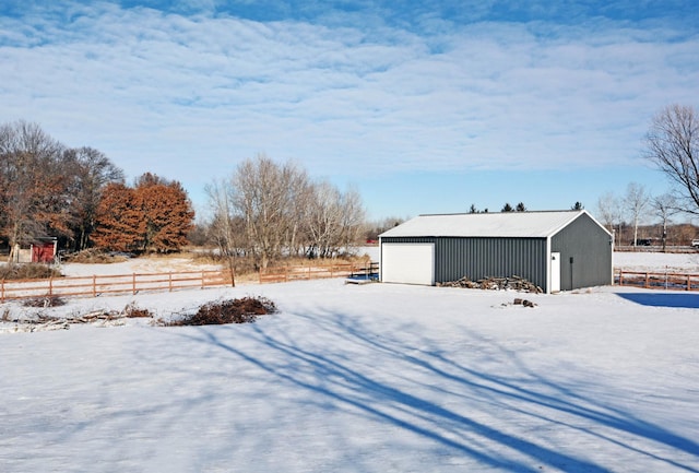 yard layered in snow featuring a garage and an outbuilding