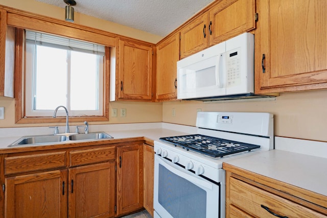 kitchen with white appliances, sink, and a textured ceiling