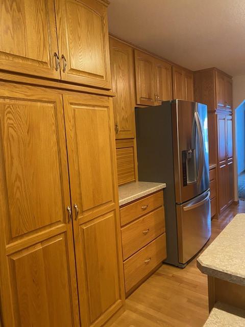 kitchen with stainless steel refrigerator with ice dispenser and light hardwood / wood-style flooring