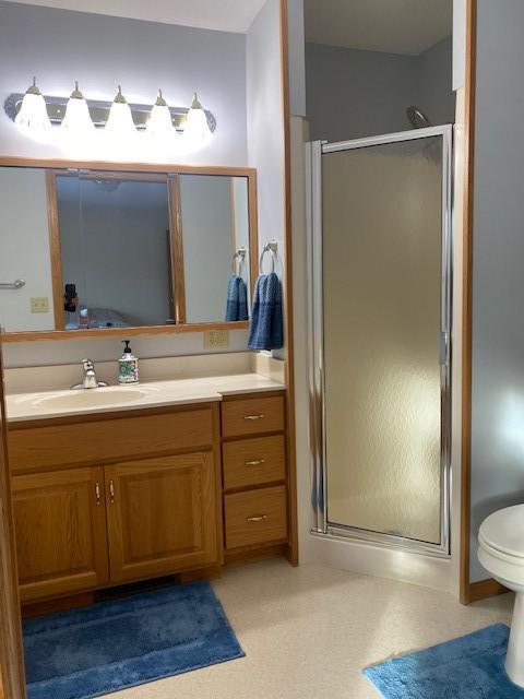 bathroom featuring walk in shower, vanity, and toilet