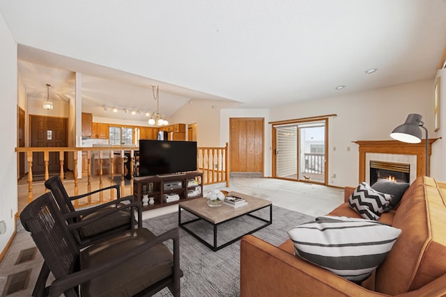 living room featuring lofted ceiling, a lit fireplace, an inviting chandelier, and light colored carpet