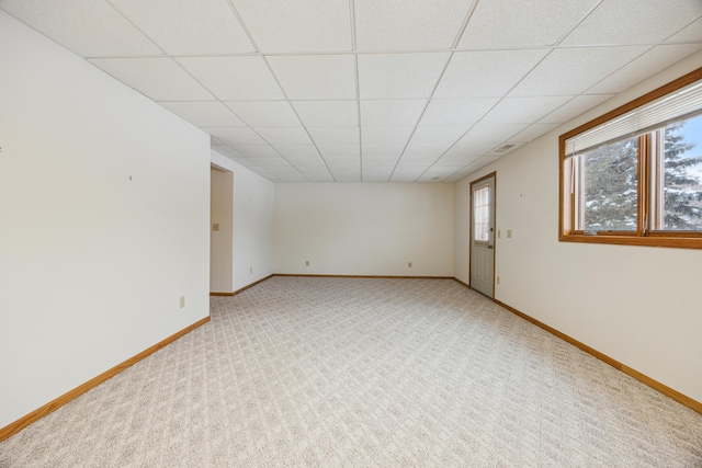 empty room featuring a drop ceiling, light colored carpet, and a healthy amount of sunlight