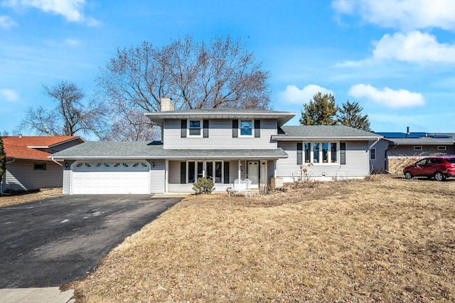 split level home featuring a garage, a chimney, aphalt driveway, a porch, and a front yard