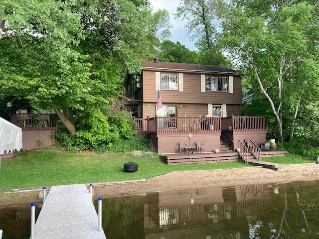 rear view of house featuring a deck with water view and a lawn