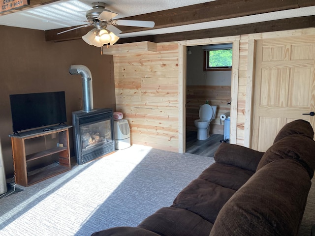 living room with a wood stove, ceiling fan, and wood walls