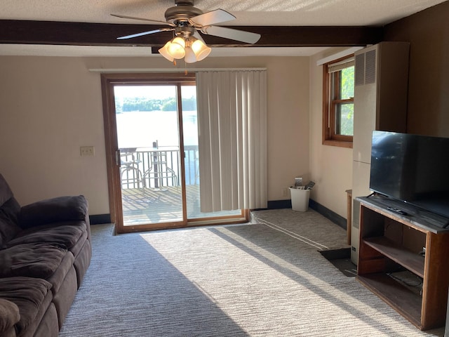 carpeted living room with ceiling fan, beam ceiling, and a textured ceiling