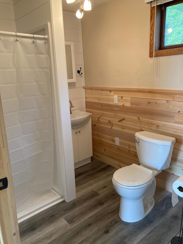 bathroom featuring toilet, wood walls, wood-type flooring, vanity, and a shower with shower curtain