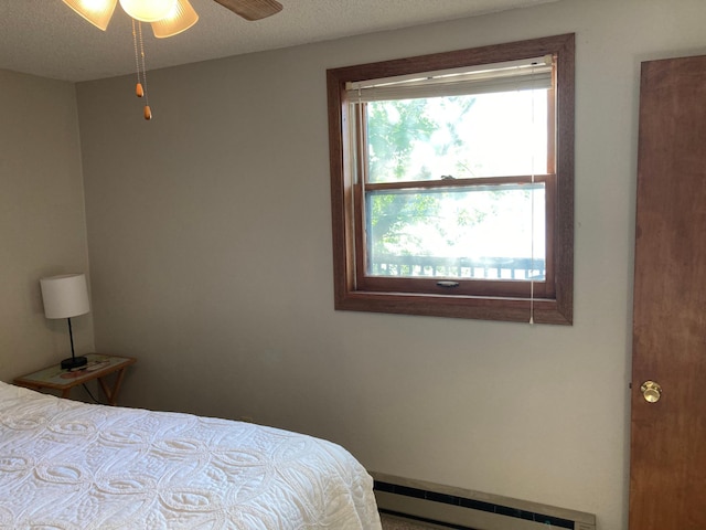 bedroom featuring a baseboard heating unit and a textured ceiling