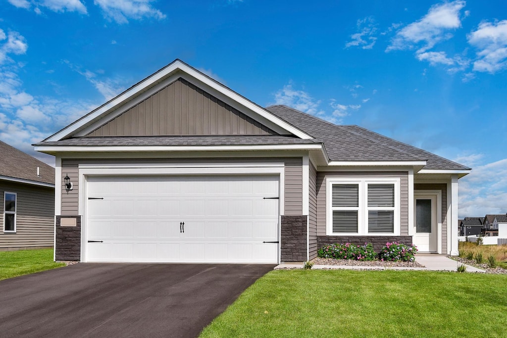 craftsman inspired home featuring a garage and a front lawn