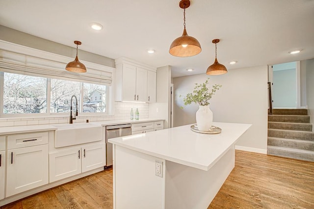 kitchen with a kitchen island, pendant lighting, sink, white cabinets, and stainless steel dishwasher