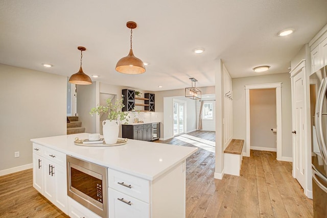 kitchen featuring white cabinetry, appliances with stainless steel finishes, a center island, and pendant lighting