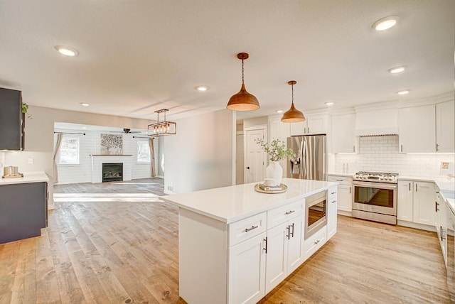 kitchen featuring decorative light fixtures, light wood-type flooring, white cabinets, and appliances with stainless steel finishes