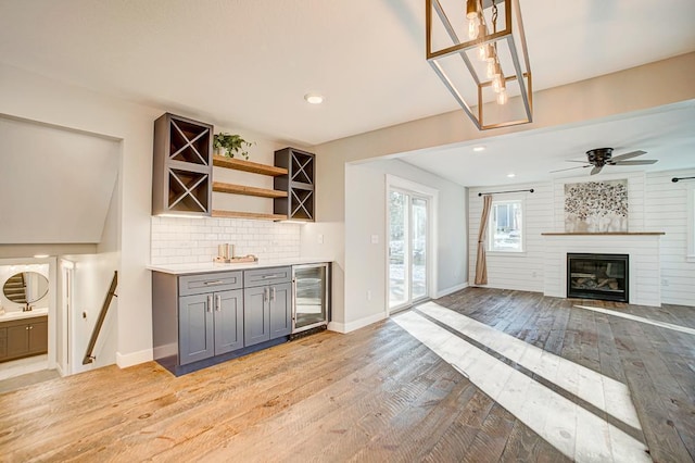 interior space featuring gray cabinets, pendant lighting, backsplash, wine cooler, and light wood-type flooring