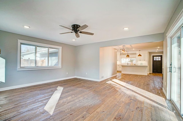 unfurnished living room featuring ceiling fan and light wood-type flooring