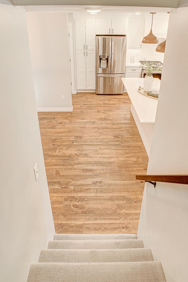 kitchen with pendant lighting, light hardwood / wood-style flooring, white cabinets, and stainless steel refrigerator with ice dispenser