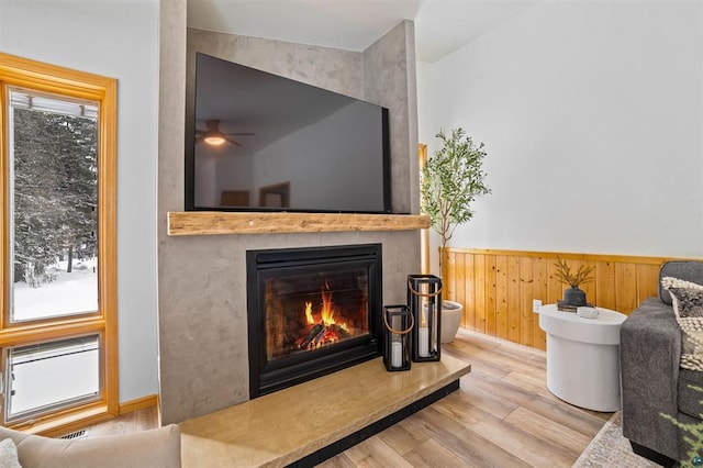 9505 Buskey Bay Dr, Iron River, WI 54847 - sitting room featuring wood finished floors, a large fireplace, a wainscoted wall, and ceiling fan