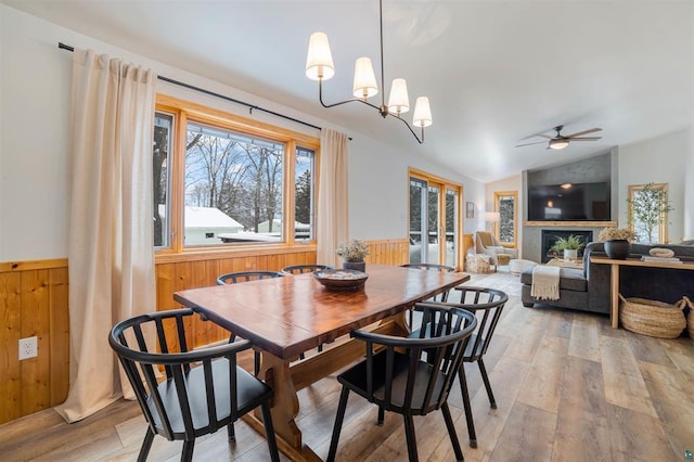 9505 Buskey Bay Dr, Iron River, WI 54847 - dining area featuring a ceiling fan, wooden walls, a wainscoted wall, lofted ceiling, and light wood-style floors