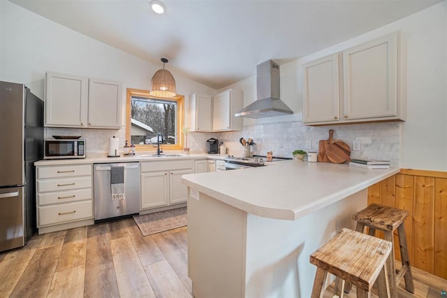 9505 Buskey Bay Dr, Iron River, WI 54847 - kitchen with wall chimney range hood, stainless steel appliances, a sink, a peninsula, and a kitchen breakfast bar