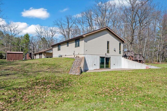 9505 Buskey Bay Dr, Iron River, WI 54847 - back of house featuring a lawn, a storage shed, and an outbuilding