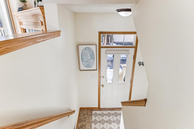 foyer featuring a textured ceiling, baseboards, and tile patterned floors