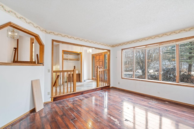 spare room with an inviting chandelier, wood-type flooring, and a textured ceiling