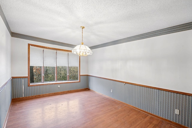 spare room with an inviting chandelier, crown molding, a textured ceiling, and light wood-type flooring