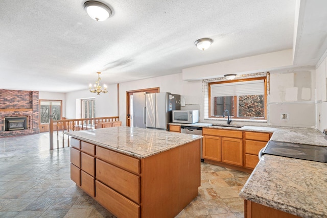 kitchen with appliances with stainless steel finishes, a center island, sink, and hanging light fixtures